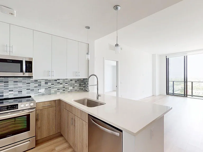Apartment Kitchen with Stainless Steel Appliances, Quartz Countertops and Wood-Style Flooring.