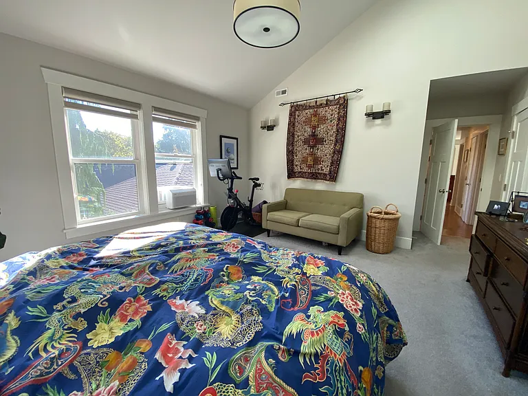 View of master suite with Peloton and couch. Large walk in closet to right (not pictured)