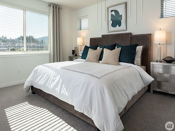 Spacious primary bedroom with large windows, abundant natural light, plush carpeting, and a peaceful atmosphere - the perfect retreat at the end of the day.