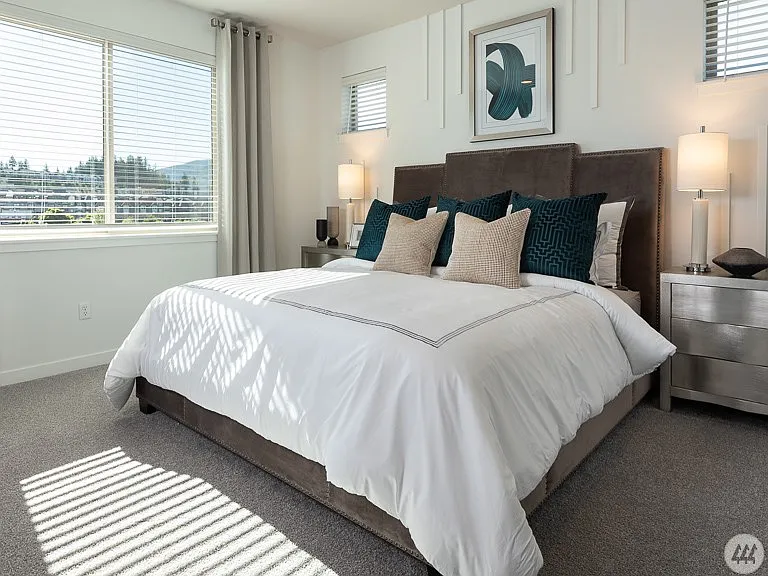 Spacious primary bedroom with large windows, abundant natural light, plush carpeting, and a peaceful atmosphere - the perfect retreat at the end of the day.