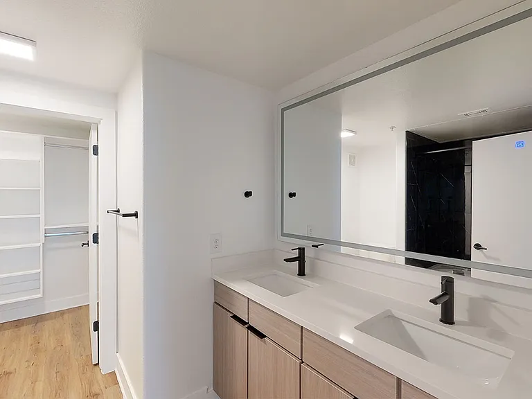 Apartment bathroom with wood-style flooring and double sinks.
