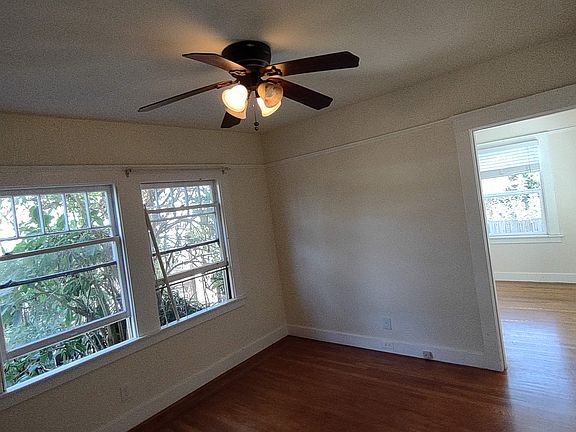 Rear Bedroom With Ceiling Fan And Windows Overlooking Backyard, Door At Right Leads To Bonus Room With Bay View