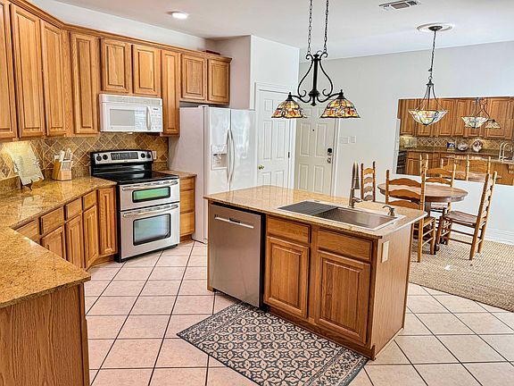 An open-concept kitchen and dining area with granite countertops, modern appliances, and stylish lighting is perfect for cooking and entertaining in a warm, inviting space.