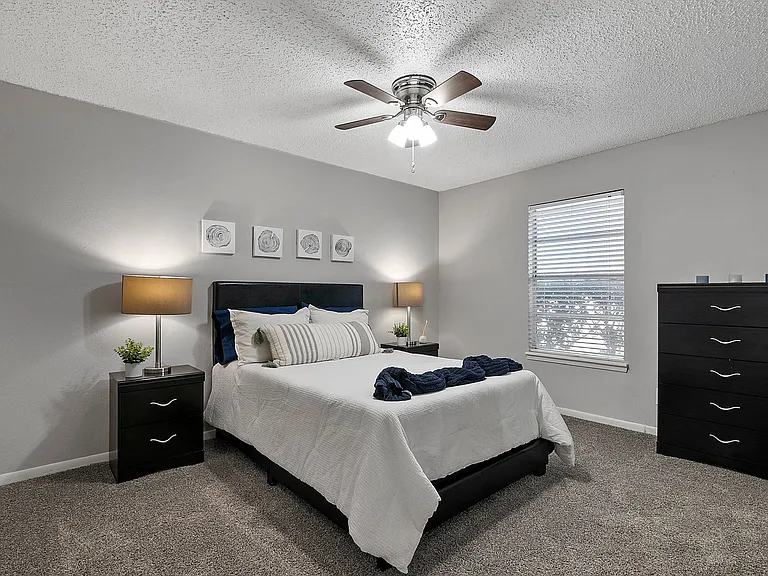 Comfortable bedroom with plush carpeting and ceiling fan for year-round comfort.