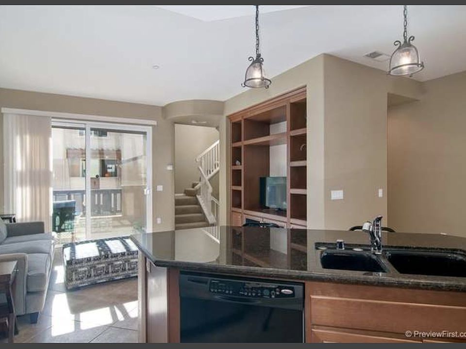 view from kitchen, living room with large bookshelf and balcony.