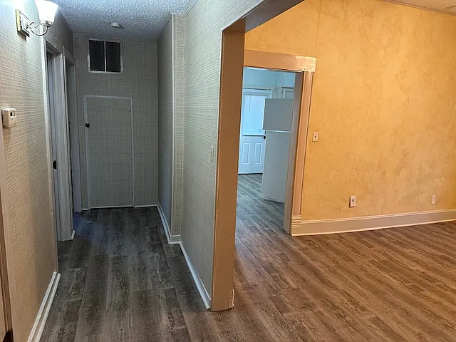 looking from living room down hallway leading to second and third bedrooms and dining room on the right, with kitchen beyond