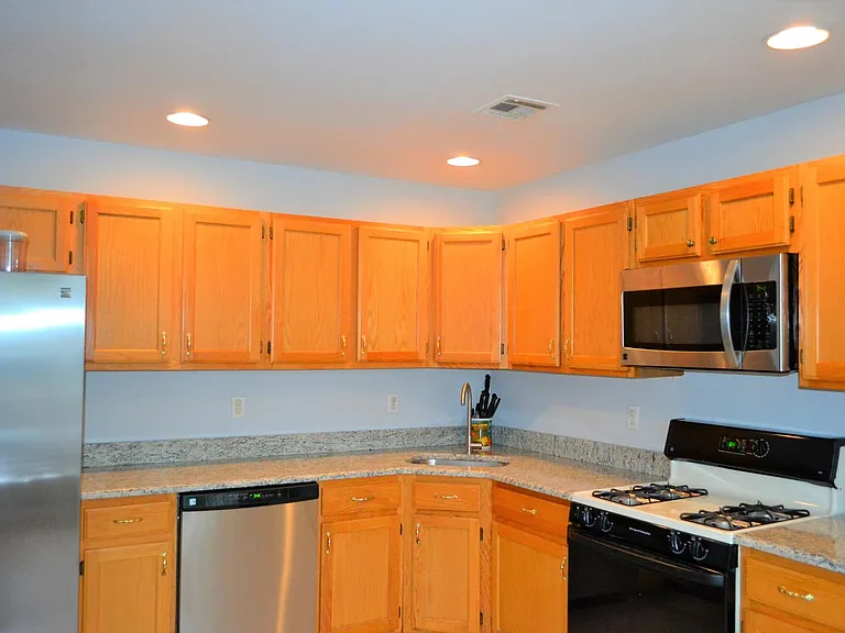 Kitchen with granite counter top, dish washer, refrigerator and cooking range