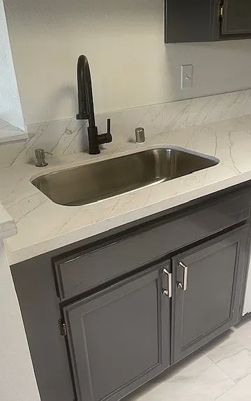 New kitchen sink with garbage disposal and dishwasher to the right. Freshly renovted cabinets.