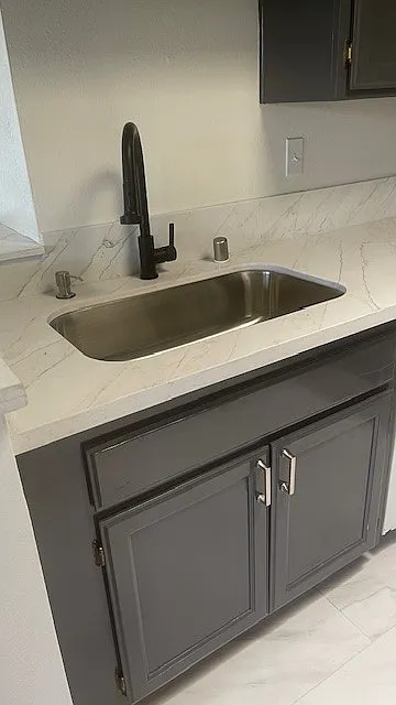 New kitchen sink with garbage disposal and dishwasher to the right. Freshly renovted cabinets.