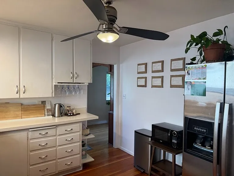 Kitchen with built-in storage drawers, a wine glass rack, shelving, and a newer refrigerator.