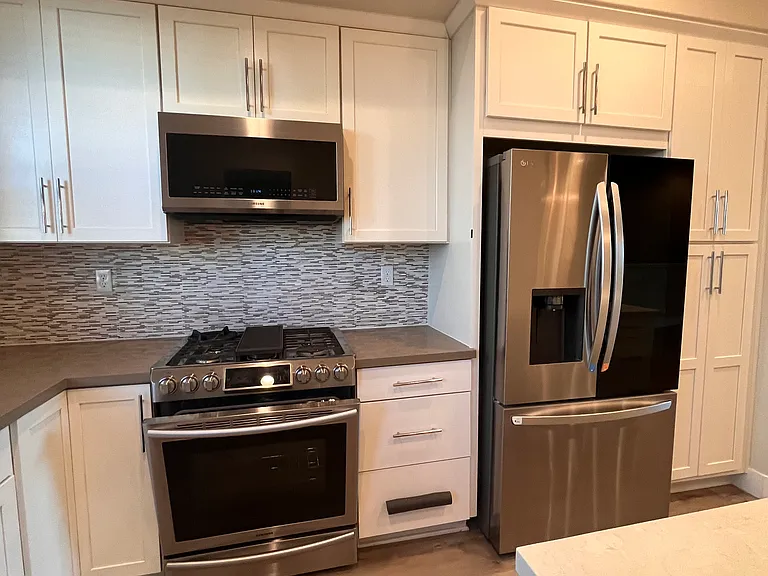 stainless steel kitchen appliance and white cabinets with fancy backsplash
