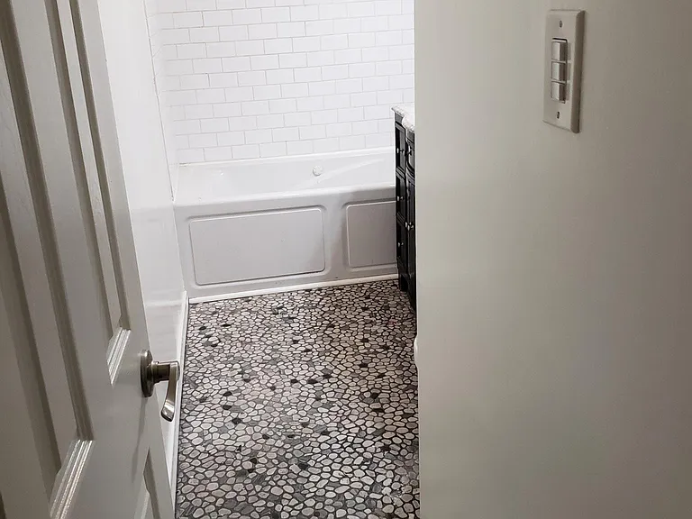 This is entering into the private bath with built in spa tub and shower, wood cabinets for storage, fan light, sky light, heater and real subway tiles