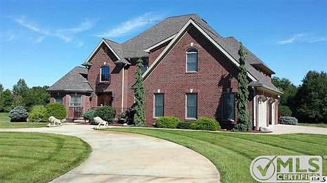 Circular drive, 3 car attached garage with decorative doors. Brick construction, wooden door, front stone patio perfect for dining al fresco or enjoying the beauty of your property. Private setting and drive, feel like you're up in Northern Michigan.
