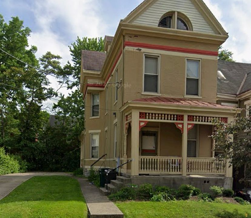 Front image of the house with large driveway, porch and side yard visible