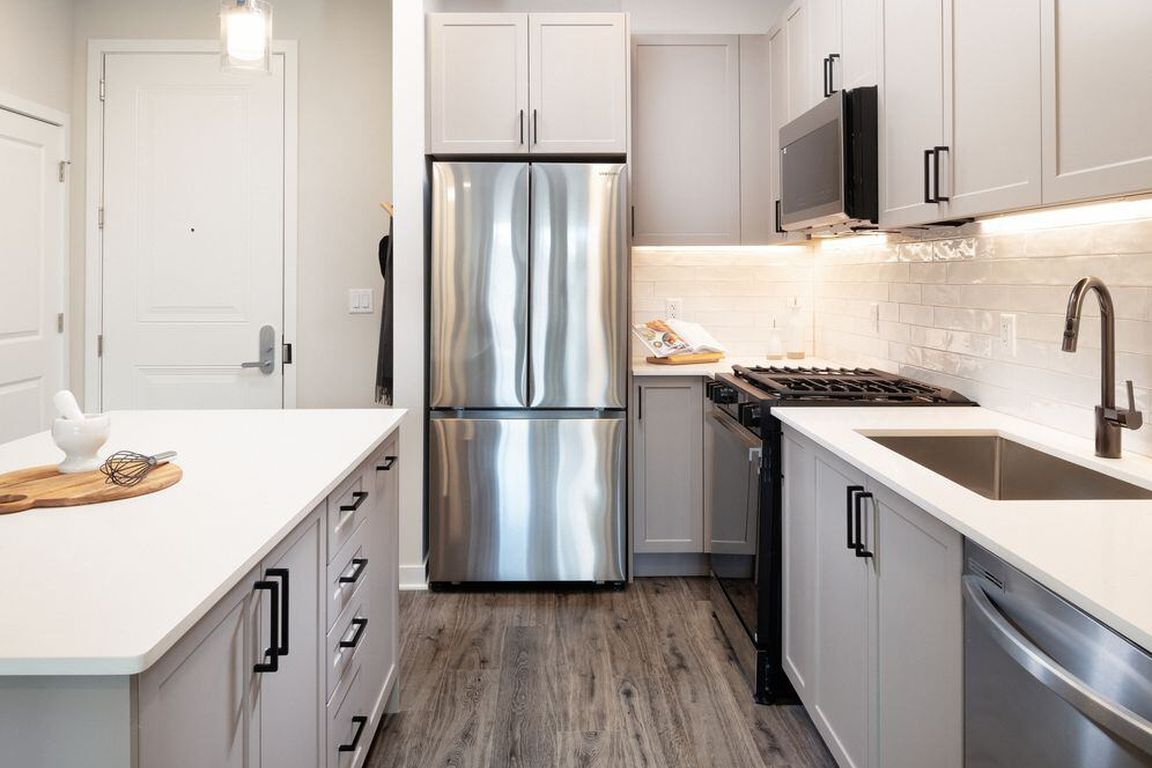 Modern with grey cabinetry, white quartz countertops, white tile backsplash, and stainless-steel appliances