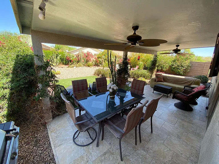 Upgraded tiled outdoor backyard with new dining table and seating for 6 plus wicker chair set and couch, ceiling fan, TV, Sedona Rock firepit, orange tree, turf to walk on and a luscious green backyard!