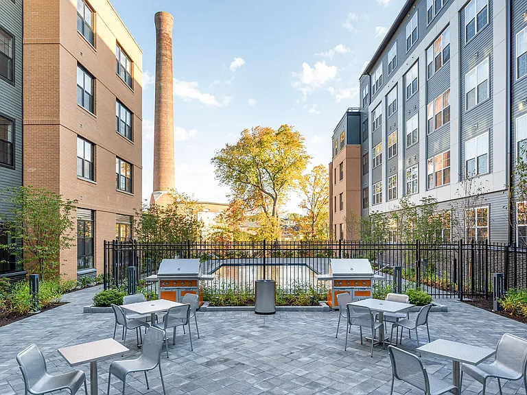 The outdoor patio adjacent to the pool features gas grills