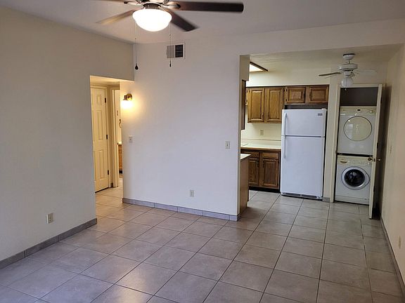 Living room with tile floor and ceiling fan. Second ceiling fan is over dining area.