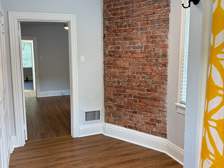 Exposed brick in bathroom looking in to second bedroom
