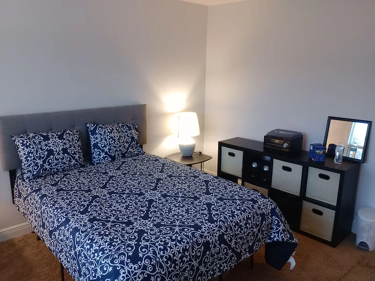 Furnished bedroom with a full/queen bed, bedside lighting, and cube storage for easy organization and daily essentials.