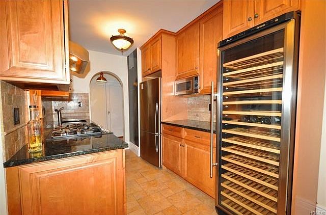 Stunning renovated eat-in-kitchen with custom cabinets, granite counters and stainless steel appliances including a dishwasher, slide-in range, microwave, refrigerator and professional wine cooler.