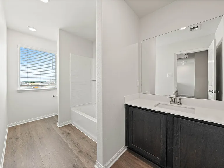 The secondary bathroom has a large vanity space and shower tub combo.