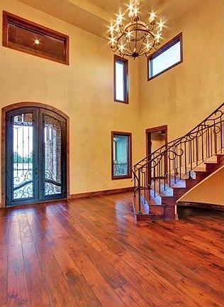 The spacious foyer, featuring the homes distinctive custom front door, soaring two-story high ceiling, and gleaming hardwood floors exhibit the careful craftsmanship and attention to detail found throughout the home.