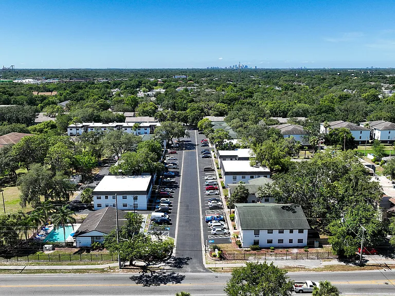 Aerial view of a charming residential area with lush greenery, well-maintained roads, and a sparkling pool inviting relaxation.