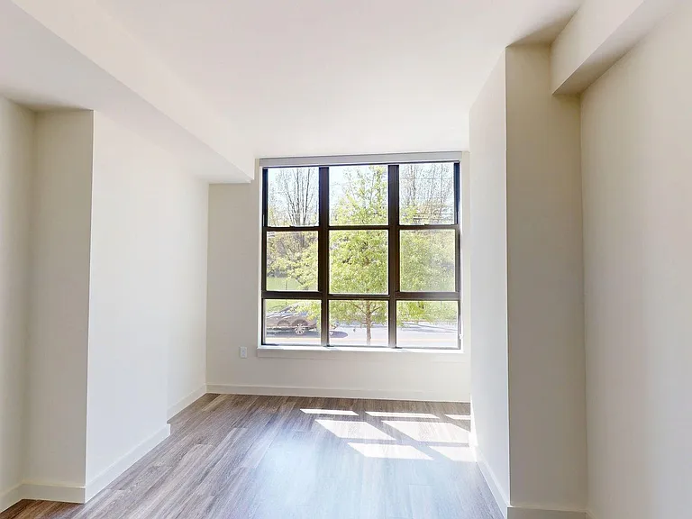 Spacious apartment bedroom with wood-style flooring.