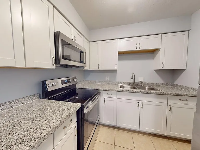 Chic modern kitchen with sleek granite countertops, stainless steel appliances, and ample white cabinetry for a stylish cooking space.