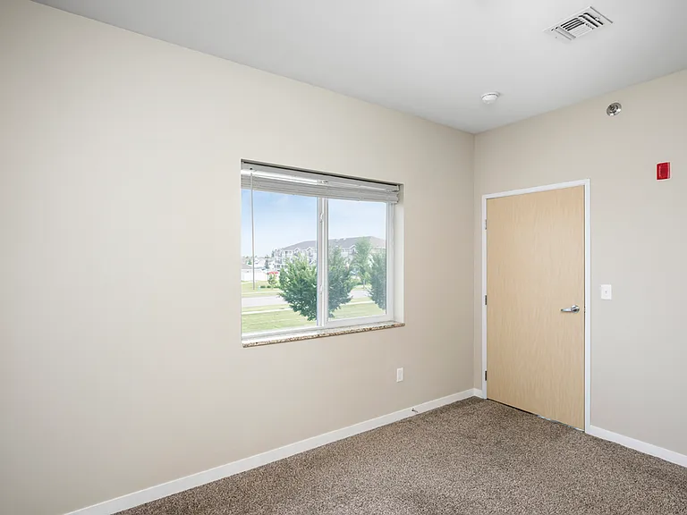Bright and airy room with a large window offering scenic outdoor views, complemented by neutral walls and plush carpet flooring. Bright and airy room with a large window offering scenic outdoor views, complemented by neutral walls and plush carpet floorin