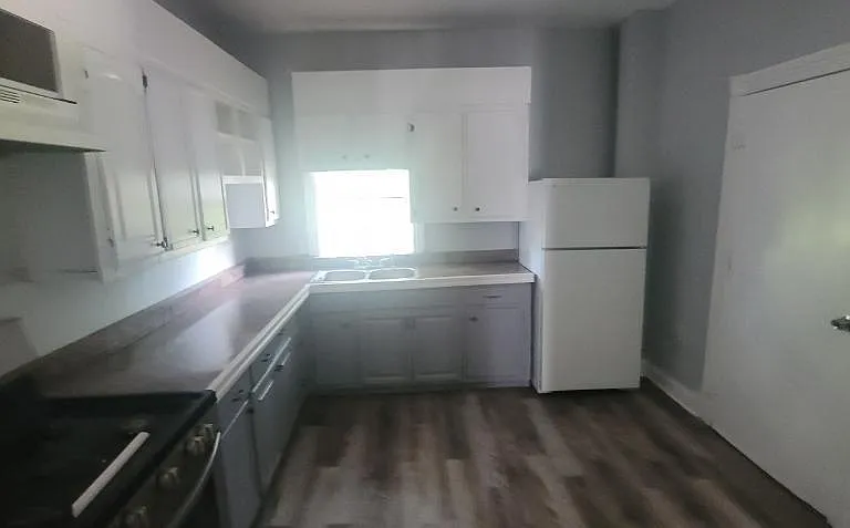 Clean, spacious kitchen w/ view of back door that leads to the back porch and rear yard area