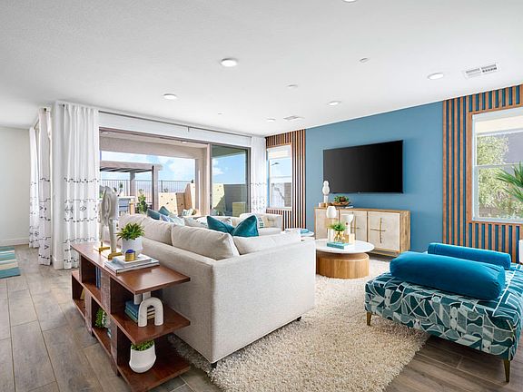 A cozy and modern living room with a white sofa, a blue patterned armchair, and a wooden entertainme