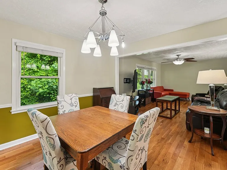 This inviting dining space feels like a sunlit storybook corner, with whimsical chairs, a graceful chandelier, and peaceful greenery just beyond the windows.