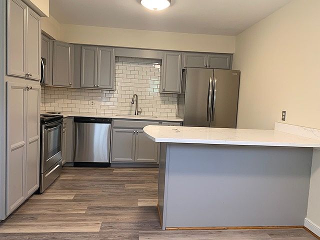 Renovated kitchen with quartz countertops and stainless steel appliances.