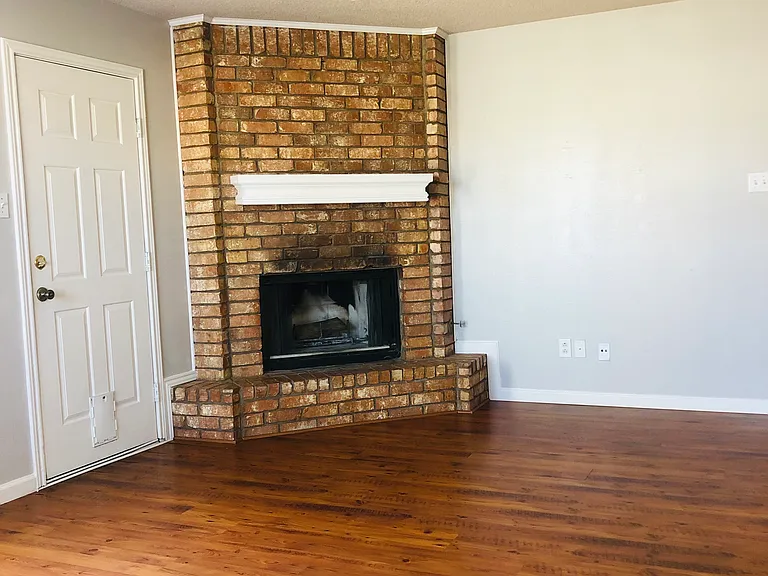 Large open living room with beautiful flooring. Wood-burning or gas burning fireplace.