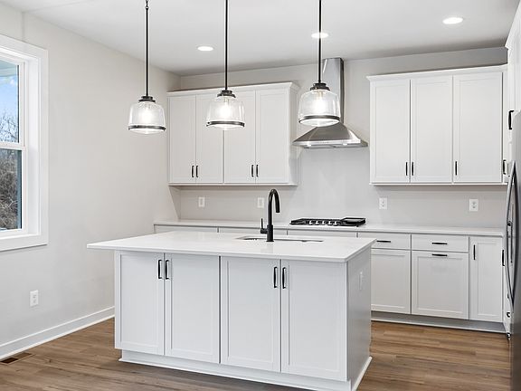 Kitchen with generous island and stainless steel appliances in a DRB Homes Beale II plan at the Trai