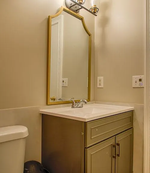 Bathroom vanity area with a single-sink cabinet, large framed mirror, and overhead light fixture for daily routines.