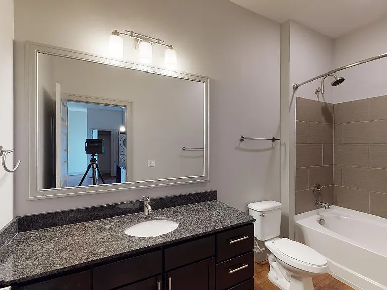 Apartment bathroom with large soaking tub and wood-style flooring.
