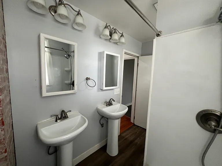 Bathroom with new sinks, lightings, medicine cabinets & exposed brick.