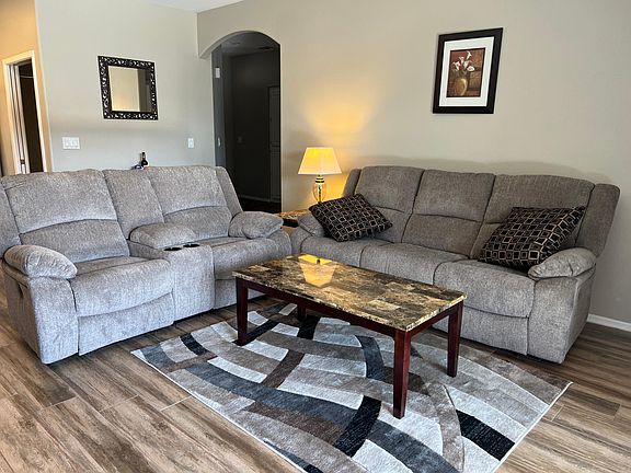 Living room with new sofa & loveseat, plank flooring.