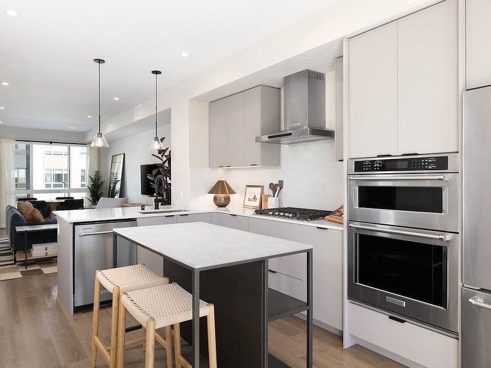Signature Collection I 3-Bedroom Townhome Kitchen with light grey cabinetry, white marbled quartz countertops, and upgraded stainless steel appliances