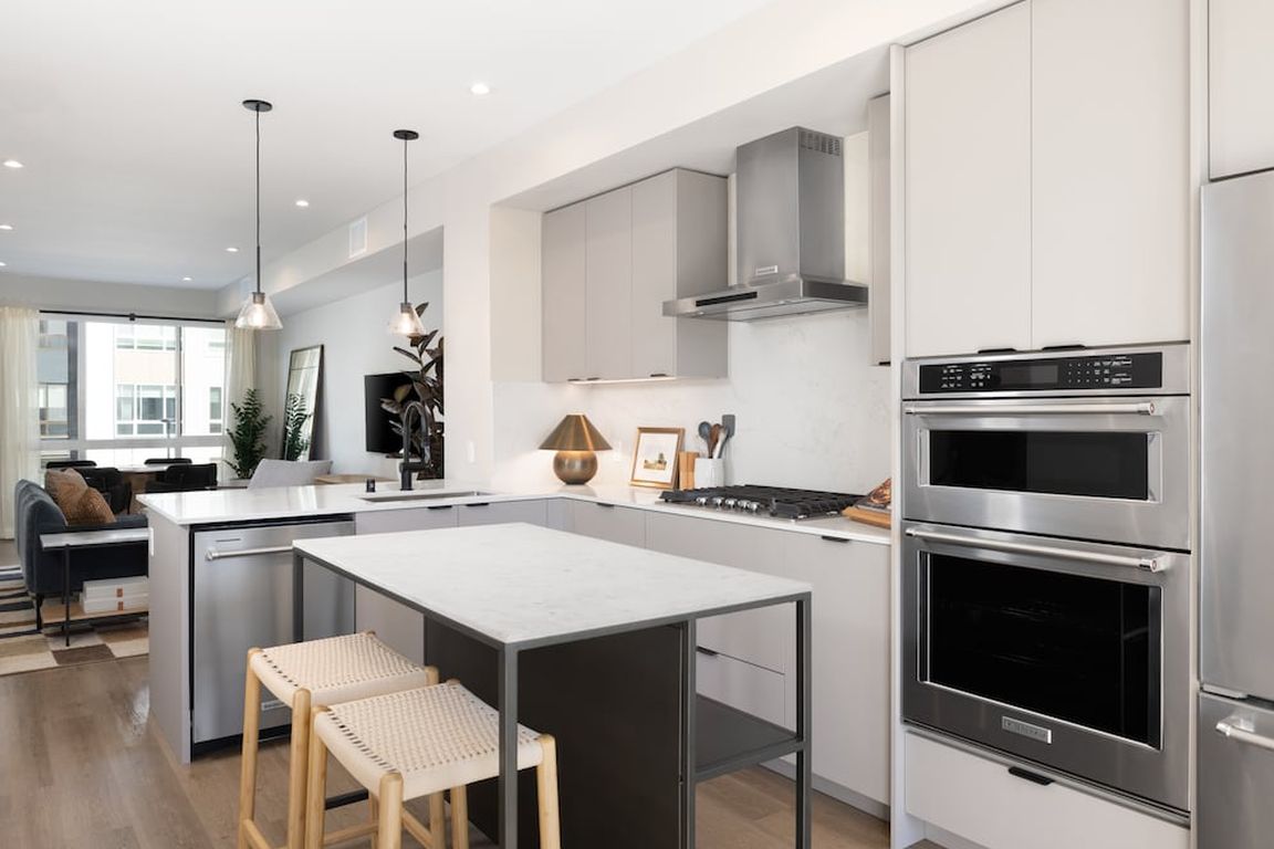 Signature Collection I 3-Bedroom Townhome Kitchen with light grey cabinetry, white marbled quartz countertops, and upgraded stainless steel appliances