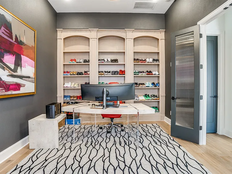 Integrated shelving unit with arched top sections and base cabinetry, light wood-finish flooring, and a modern door with reeded glass paneling