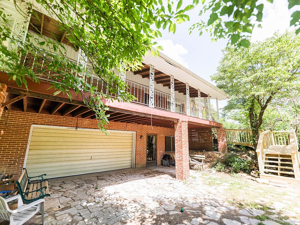 Back of house showing covered deck, new stairs , garage, and door to finished walk-out basement