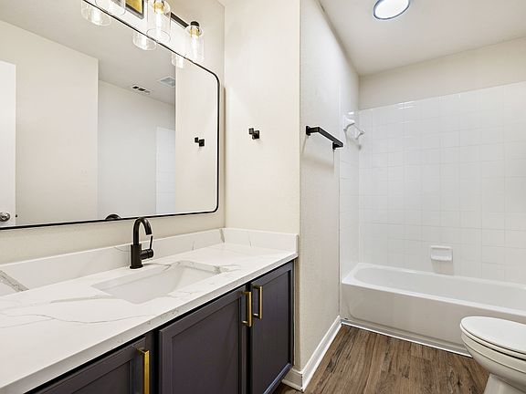 Secondary remodeled bathroom, with elegant vanity with quartz countertop and modern fixtures