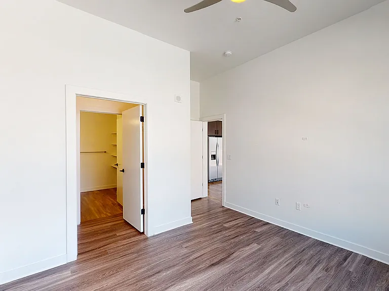 Spacious apartment bedroom with large closet and wood-style flooring.