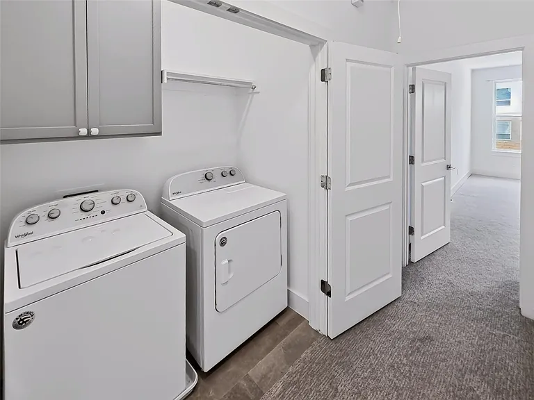 Dedicated laundry area featuring overhead cabinetry, a clothing rod, and wood-finish flooring