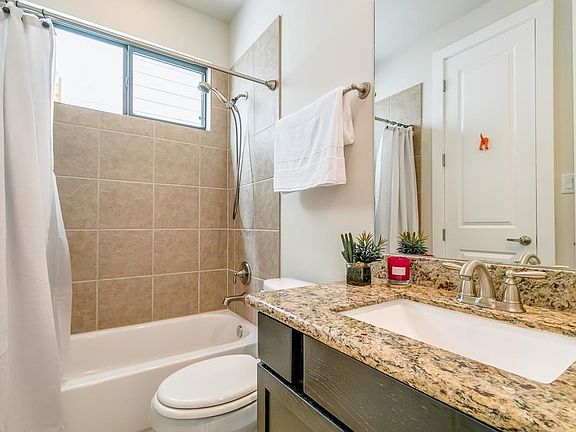 Full bath on first level featuring granite counters and neutral tiles.