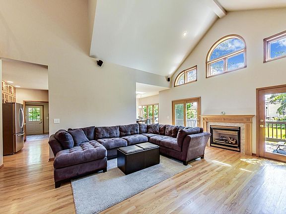 Large living room with soaring cathedral ceilings and a gas fireplace opens to a huge back deck